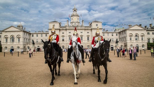 A close-up view of the ceremonial uniforms and helmets of two Household Cavalry mounted guards standing outside the museum building