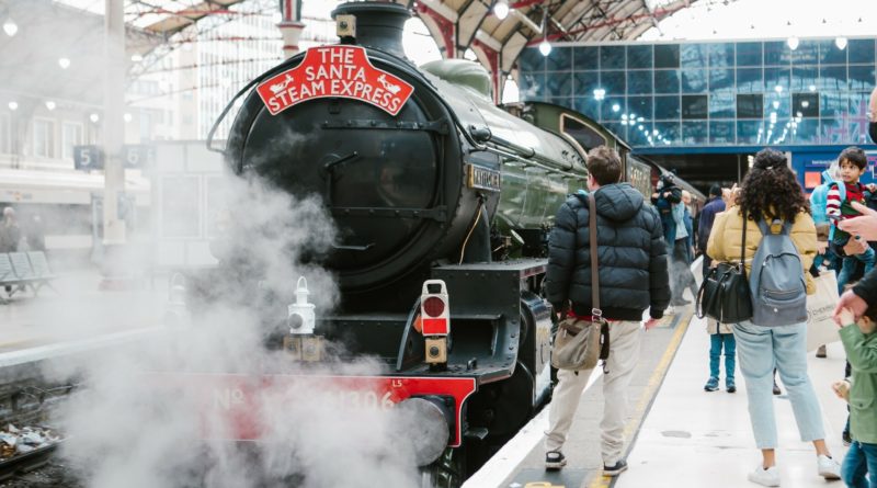 The Santa Steam Express train at a station with passengers waiting, steam rising from the engine